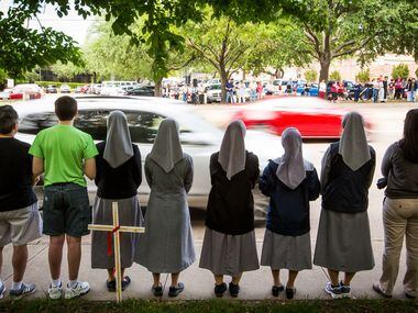 Abortion opponents line the sidewalk in prayer as traffic passes on Greenville Avenue during...