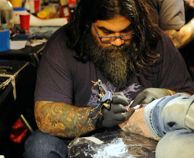 A tattoo artist is at work during the Elm Street Tattoo and Music Festival in Deep Ellum.