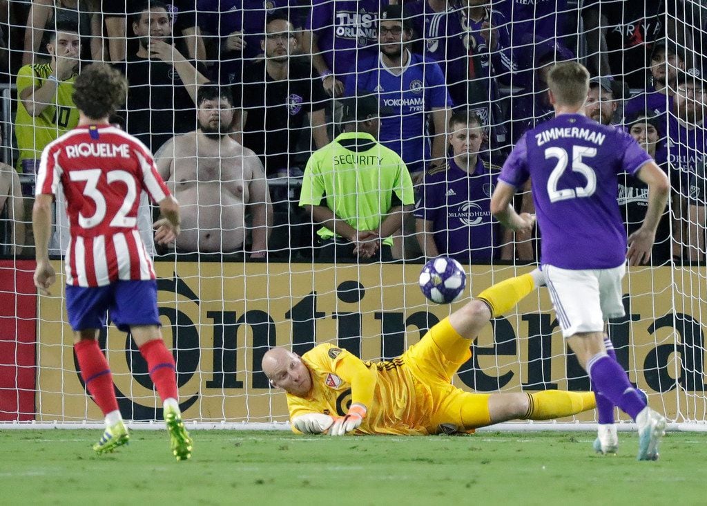 Atlanta United goalkeeper Brad Guzan, center, blocks a shot by Atletico Madrid midfielder...