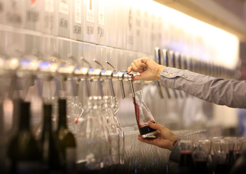 A bartender taps wine.