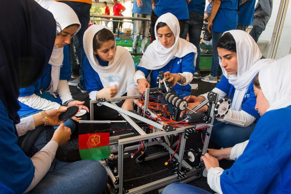 Members of the Afghani all-girls robotics team make adjustments to the team robot in the...