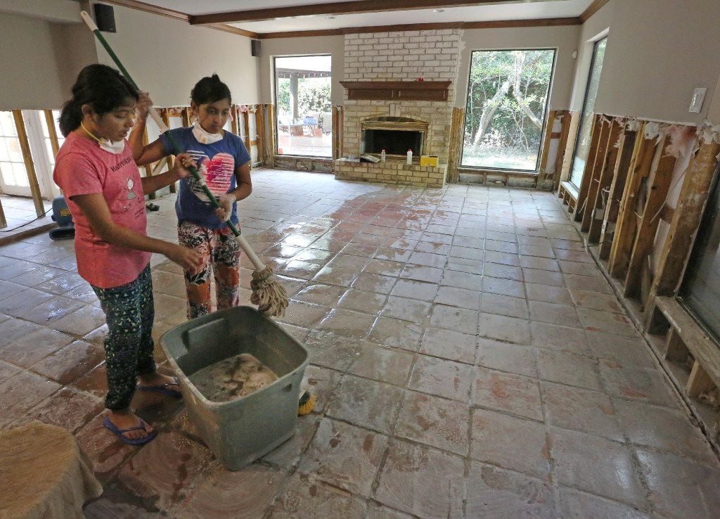 Twin sisters Saloni and Sugani Singh, 10, share mopping duties as they work to clean up...