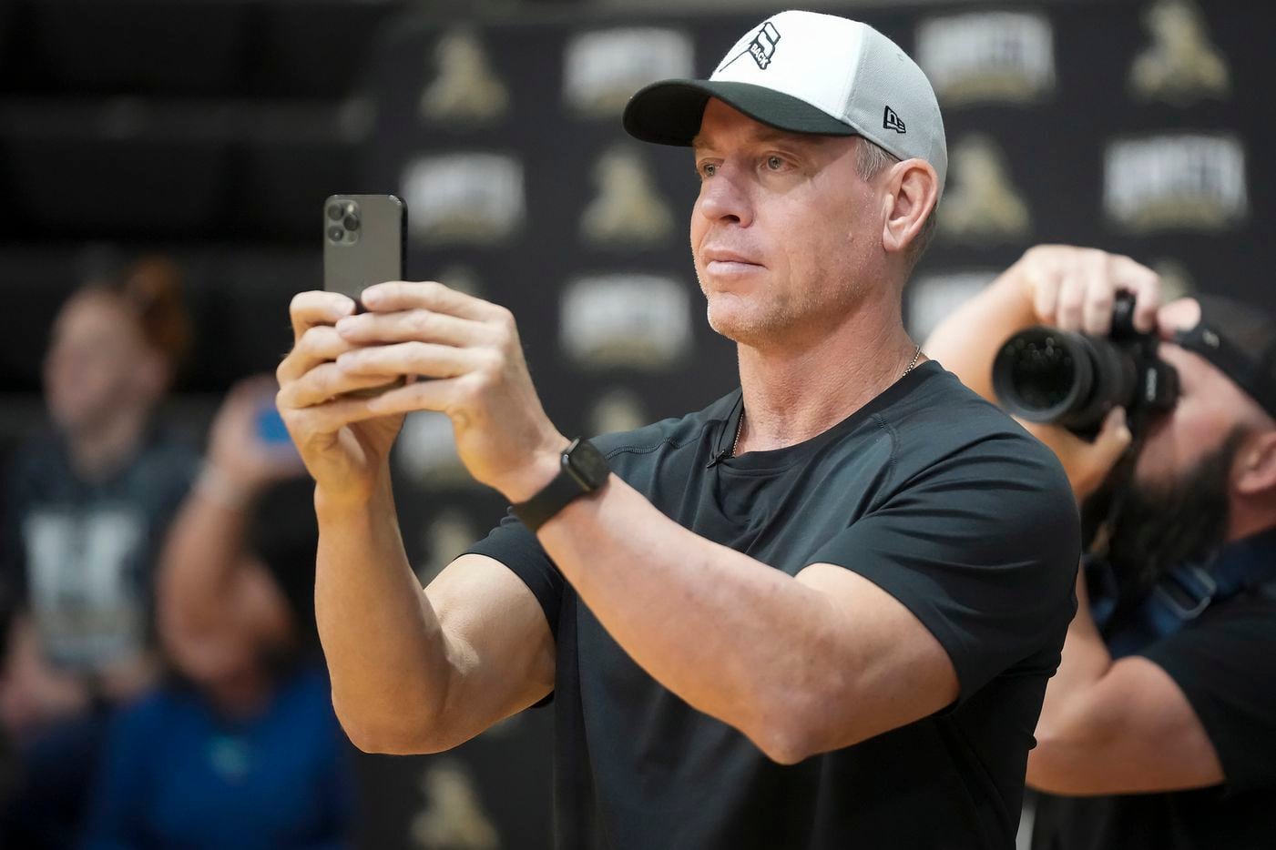 Troy Aikman records a performance by students  during the pep rally.