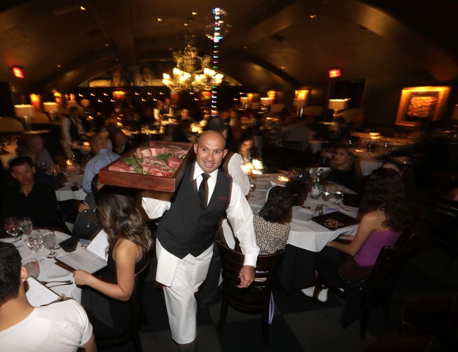 Waiter Alen Couoh carries meat at Nick & Sam's Steakhouse in Dallas. Here, dinner almost always comes with a show.