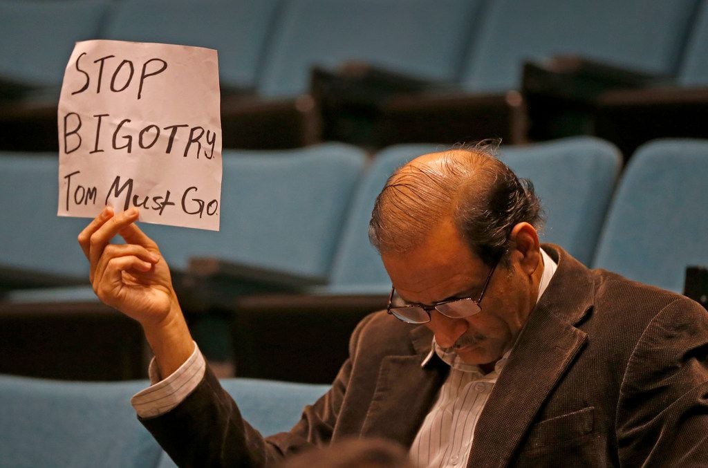 Plano resident Hasan Waqar holds up a sign while Mayor Harry LaRosiliere speaks during a...