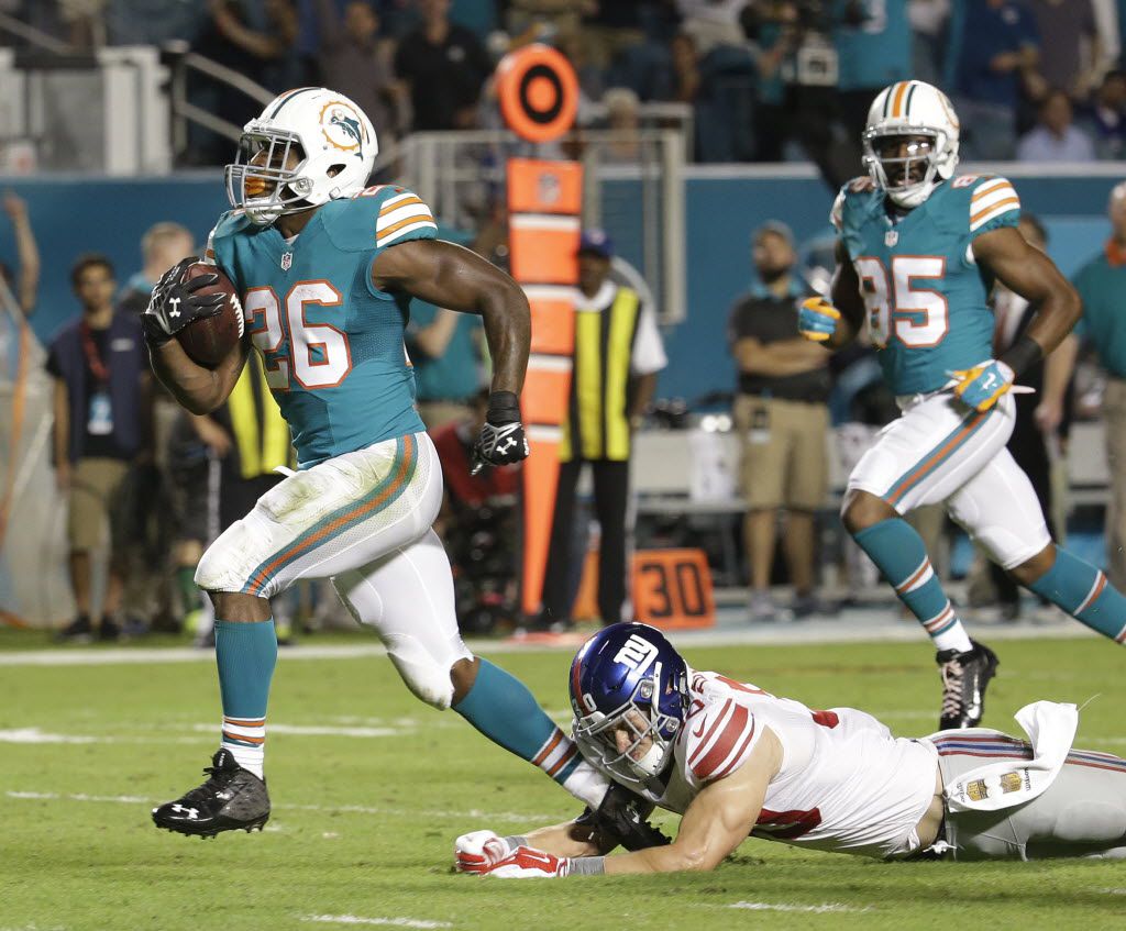 Miami Dolphins running back Lamar Miller (26) breaks a tackle by New York Giants defensive...