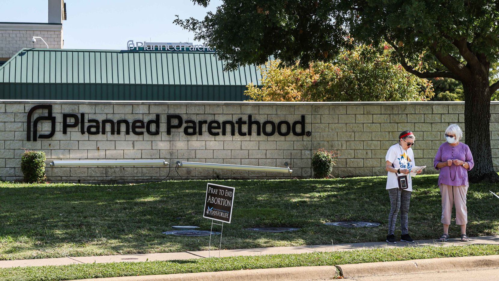 A couple of protesters stands on the sidewalk near Planned Parenthood next to anti-abortion...