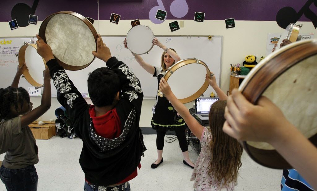 Karen Becker (center) uses tambourines in a mirroring exercise in her third-grade music...