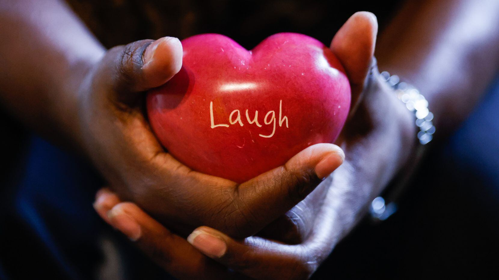 Ayana Brown, a Navy veteran, holds a a heart-shaped stone with the word "laugh" engraved in...