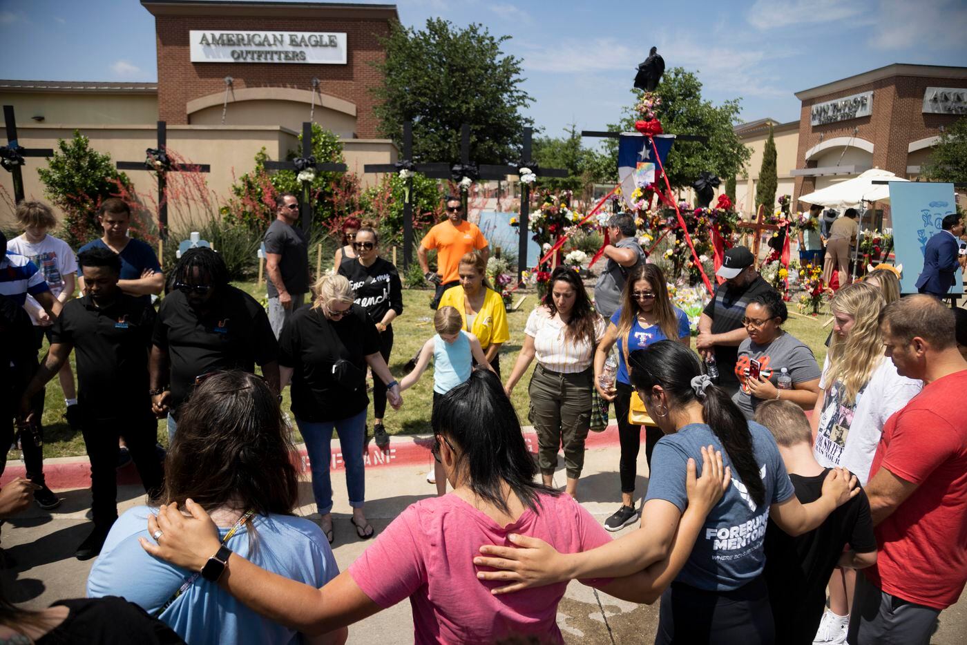 People pray at a memorial outside the mall after a mass shooting at Allen Premium Outlets in...