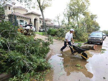 Spencer McIntyre wheels a piece of tree trunk k to the curb after a tornado spawned by...