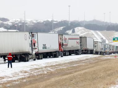 A pair of truck drivers stand along westbound I-20 near Loop 408 after several vehicles were...