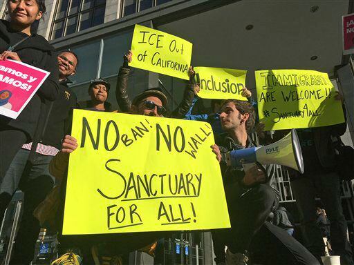 Manifestantes sostienen letreros a las afueras de una corte en la que un juez federal...