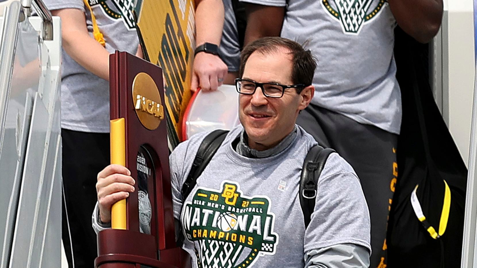 Baylor men's basketball Head Coach Scott Drew carries the NCAA Division I National Championship trophy as he exits the plane Tuesday, April 6, 2021, in Waco, Texas.