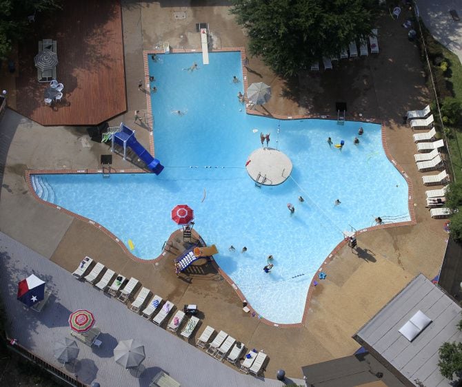 Swimmers enjoy The Texas Pool, a pool shaped like the state of Texas, located at 901 Springbrook Dr. in Plano, Texas. Two swimmers leap from a platform in the center of the pool on a very hot summer day Friday, June 22, 2012.
