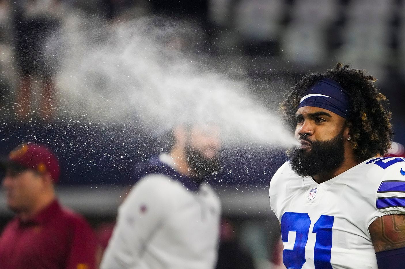 Dallas Cowboys running back Ezekiel Elliott blows water while warming up before an NFL football game against the Washington Football Team at AT&T Stadium on Sunday, Dec. 26, 2021, in Arlington.