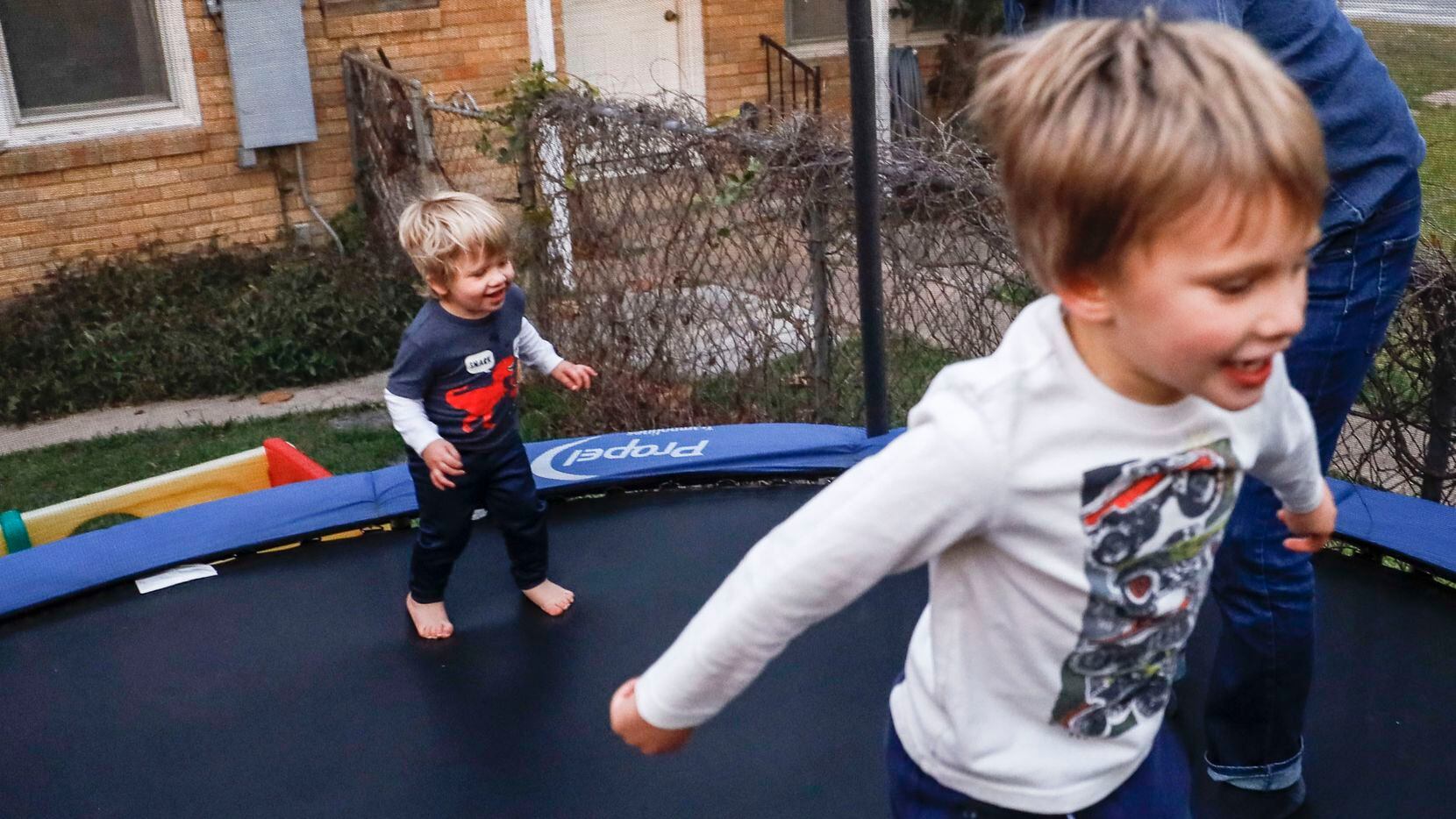 Craig Hoffman plays with his son Roky, 2, as River, 4, jumps next to them on the trampoline...