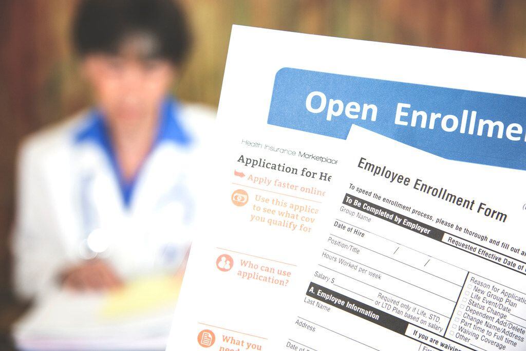 Patient holding open enrollment healthcare benefits forms with a medical doctor in the...