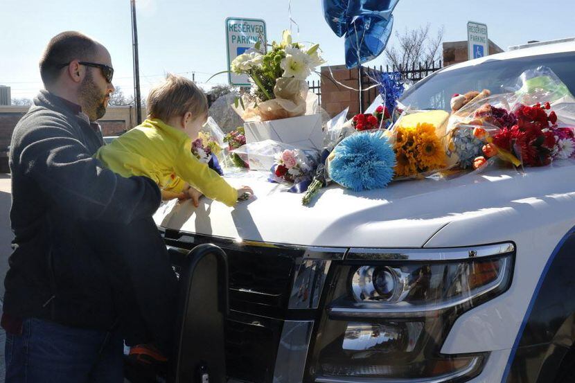 Kevin Goldsmith y su hijo Henry dejan flores en un patrullero policial en homenaje a David...
