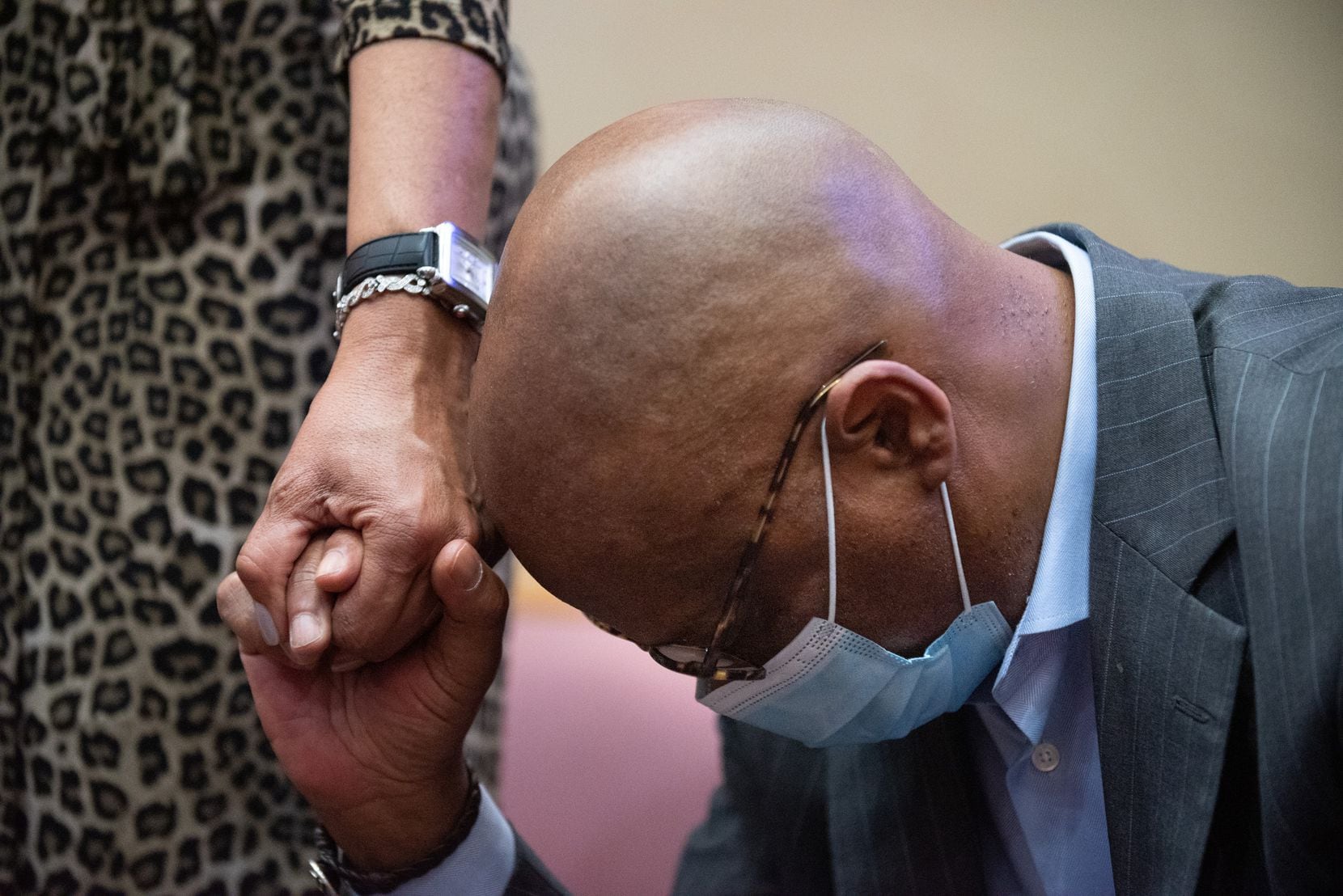 Church member Michael Cleaver bows his head while holding Rozalind Cleaver's hand during a...