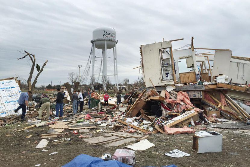 Voluntarios forman una fila mientras remueven escombros de los tornados que arrasaron...
