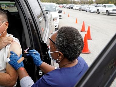 Mary Mbogo gives Victor Rendon a COVID-19 shot at the drive-through vaccination site at Fair Park in Dallas on Nov. 21.