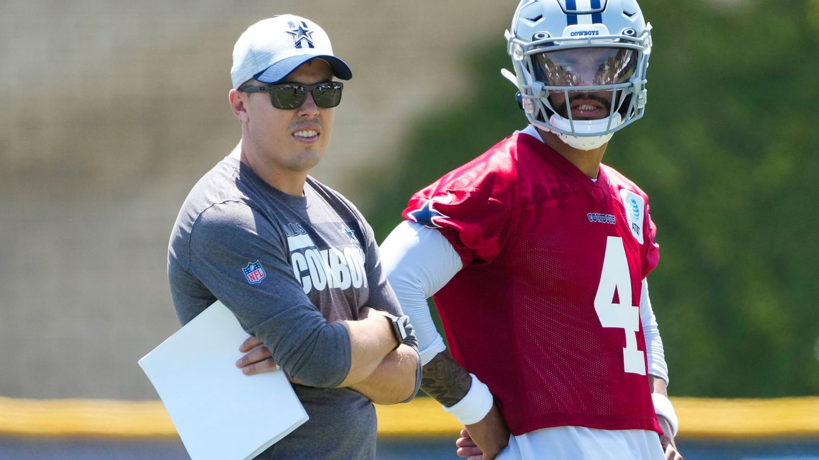 Dallas Cowboys quarterback Dak Prescott (4) talks with offensive coordinator Kellen Moore during the first practice of the team’s training camp on Thursday, July 22, 2021, in Oxnard, Calif.