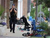 A Lake County police officer walks down Central Ave in Highland Park, Ill. on Monday, July...