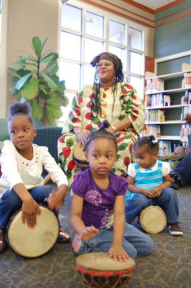 Afiah Bey is pictured in this photo, showing her surrounded by children holding drums during one of her performances.