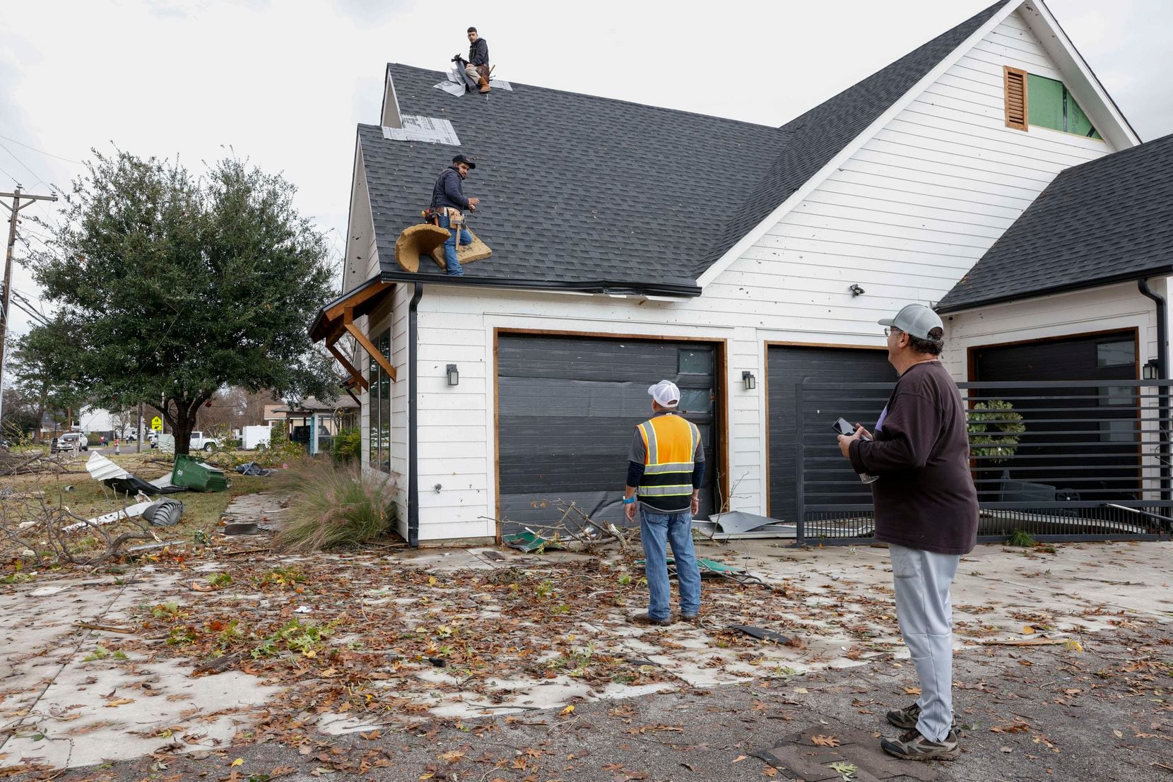 Homeowner Randy Popiel (right) watches as Banner Roofing employees work to repair his roof...