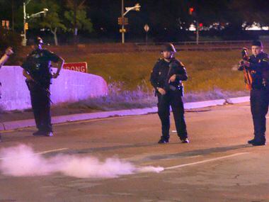 A Dallas police officer fires pepper balls at a crowd during Monday night's protest against...
