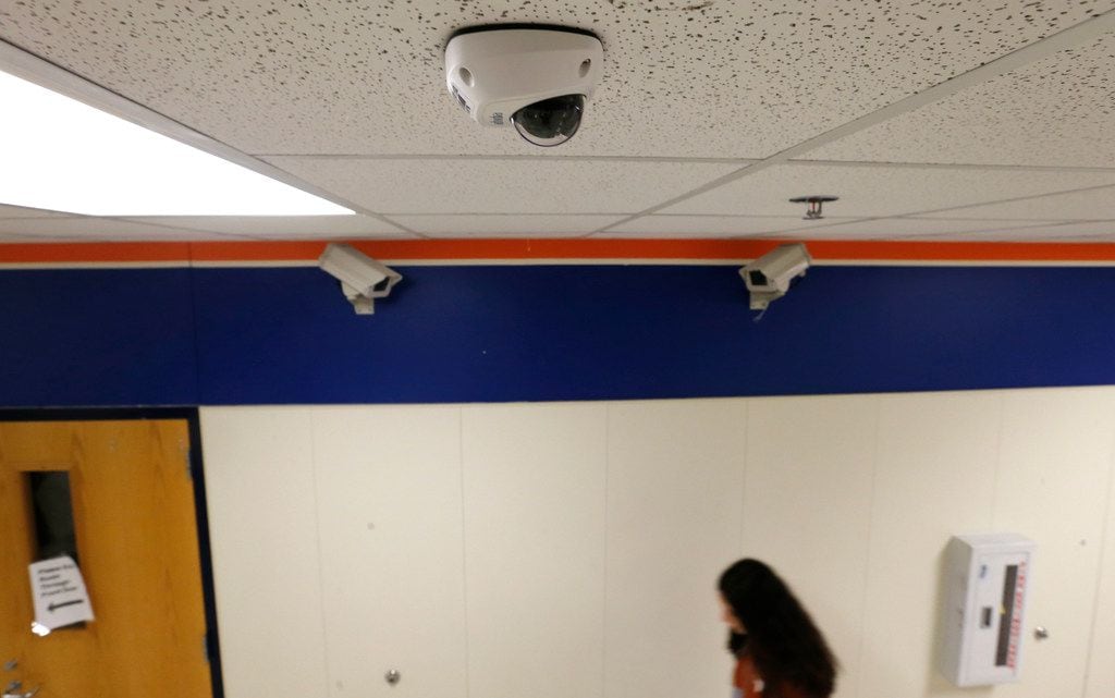 A student passes one of the new security cameras in a hallway near two of the older models...