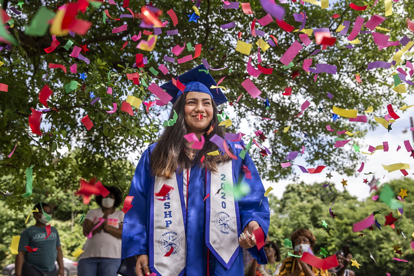 High school graduate Areisy Saucedo smiles in surprise as local residents shower her in...