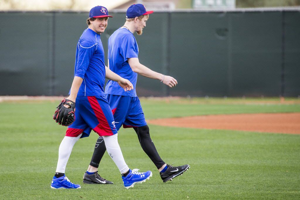Texas Rangers pitcher Derek Holland (left) walks across a practice field with Jake Diekman...