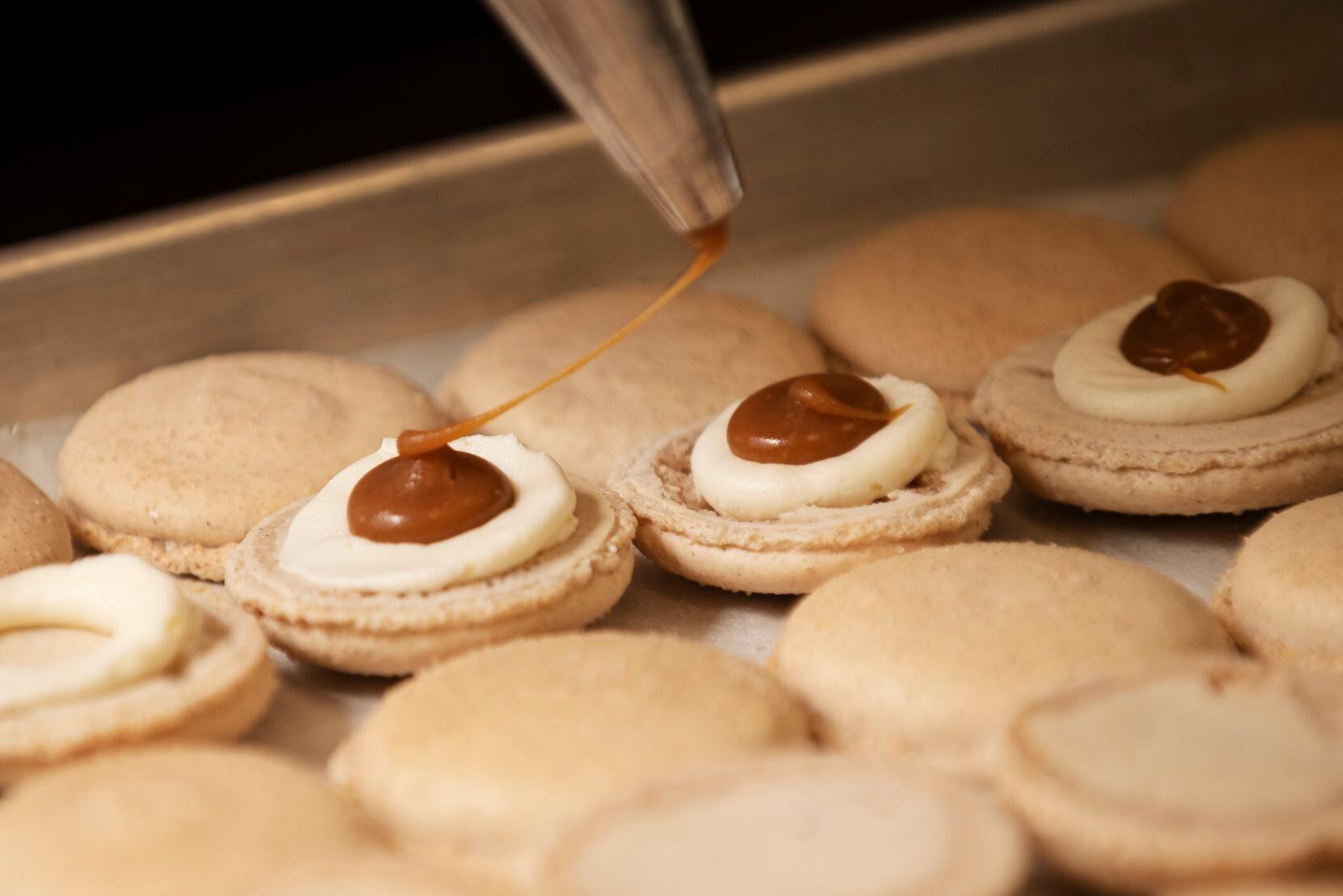 Andrea Meyer, of Bisous Bisous Patisserie, pipes churro-flavored filling on macarons. 