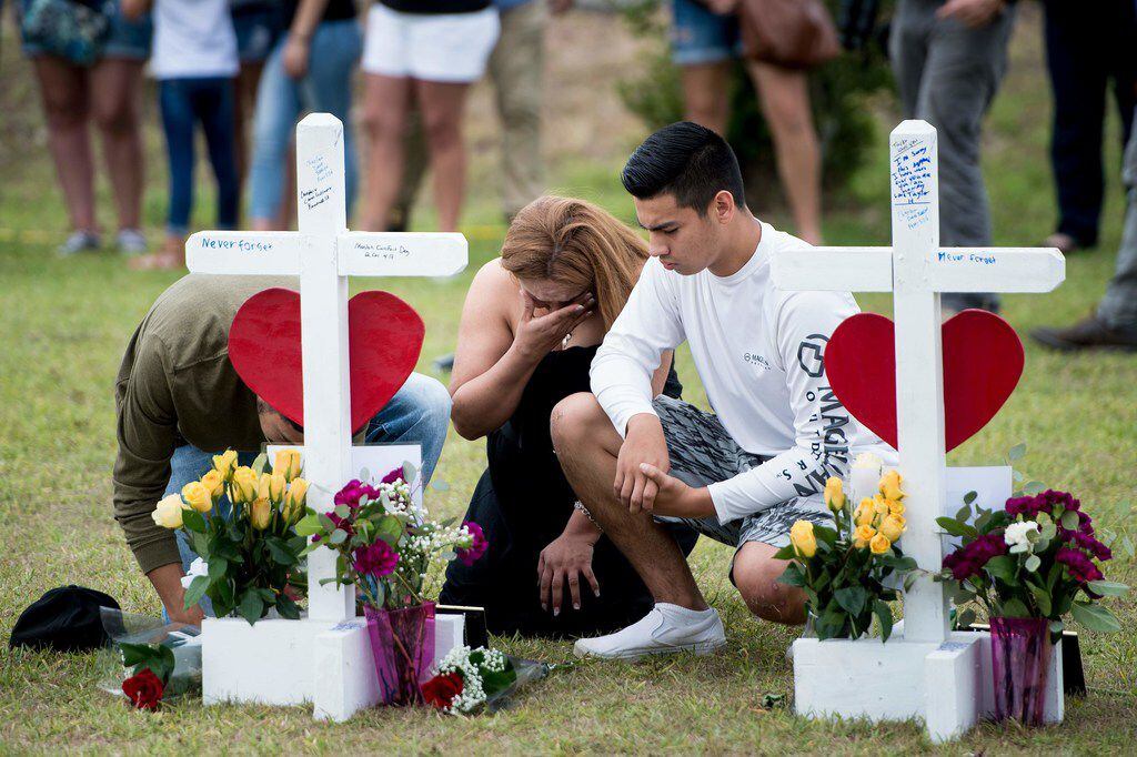 People visit a cross for Christopher Stone at a memorial for the victims of the Santa Fe...