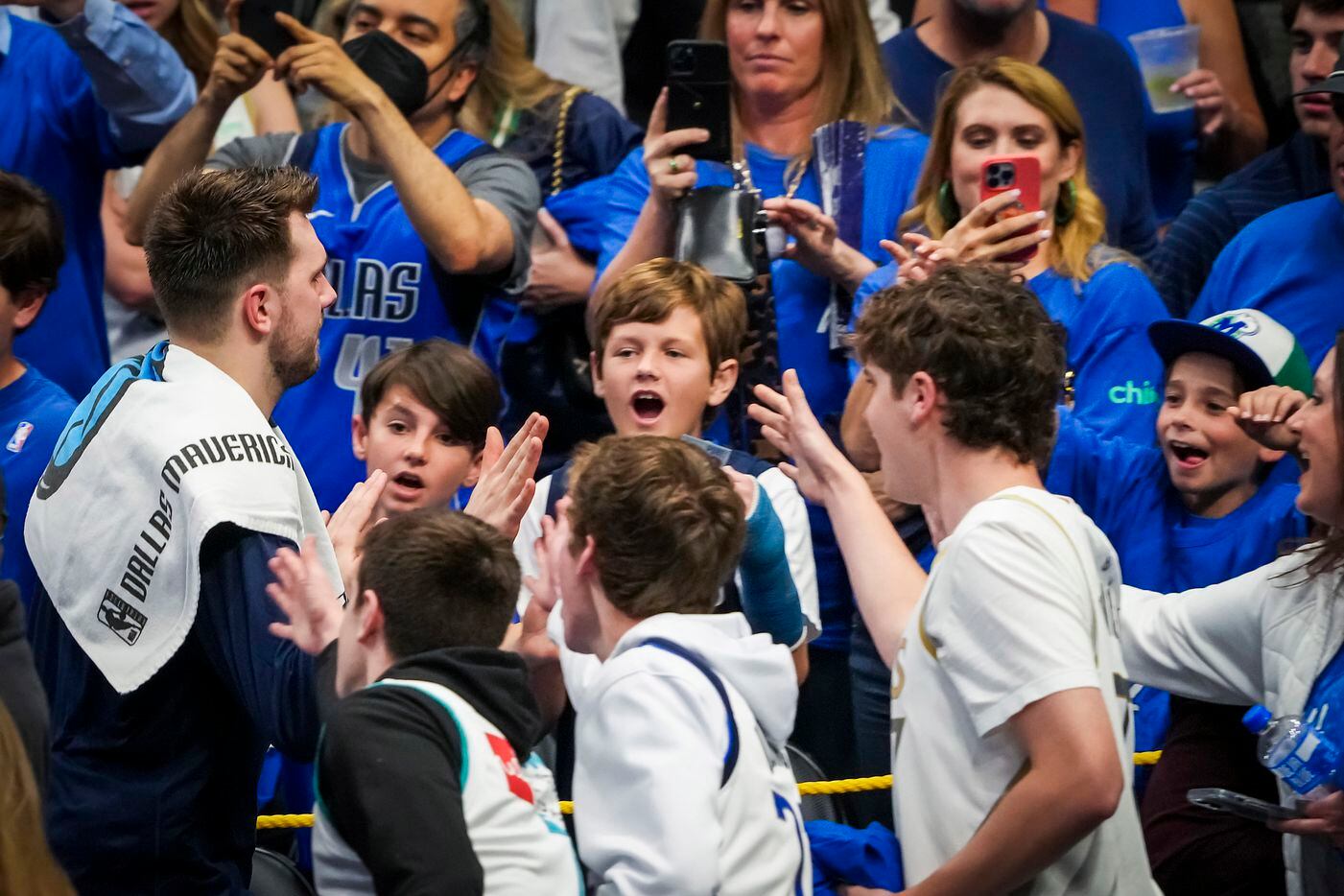 Dallas Mavericks guard Luka Doncic high fives fans as he leaves the court after a victory...