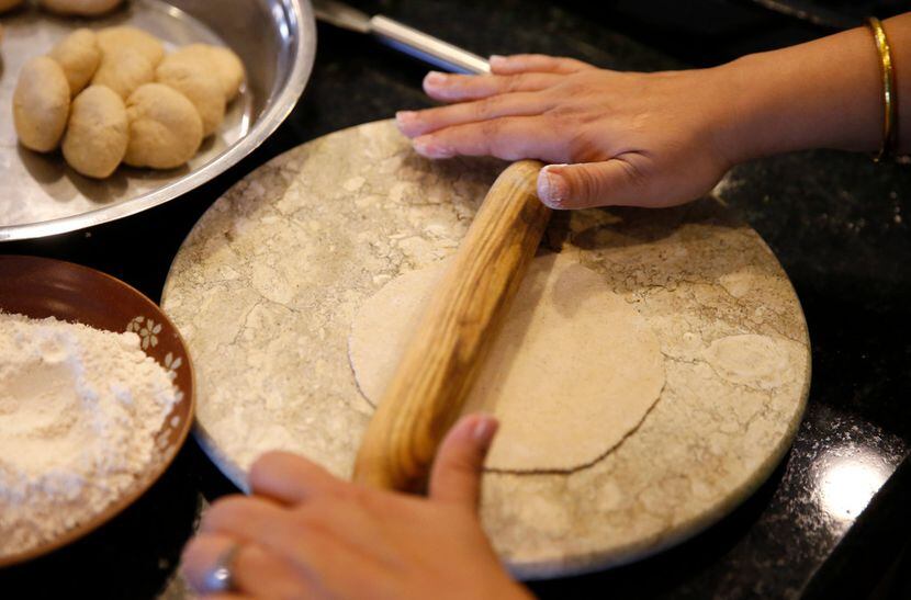 Sapna Punjabi-Gupta rolls out a ball of dough as she prepares to cook roti.
