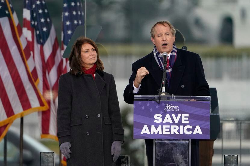 Texas Attorney General Ken Paxton speaks as his wife, state Sen. Angela Paxton watches on...