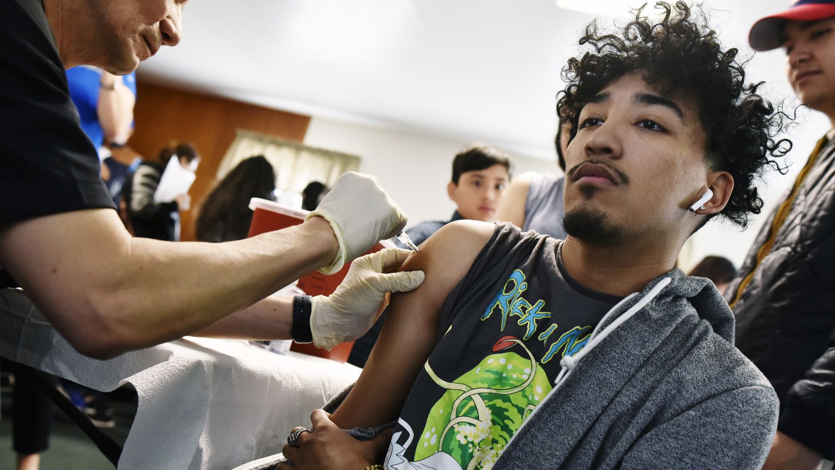 Alan Calvillo, 19, right, receives a flu shot from Medical Doctor Philip Huang, Director of...
