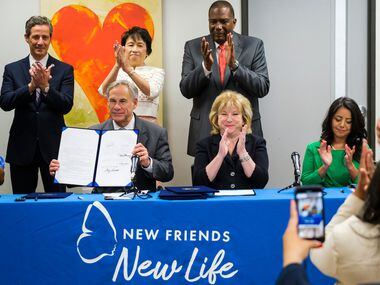 Governor Greg Abbott holds up House Bill 1590 after signing the legislation during a bill...