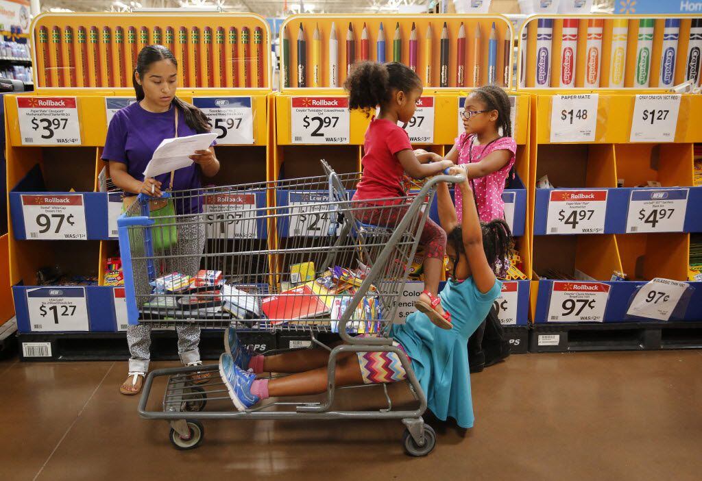 Maria Rice of Little Elm (left) looks over her school supply lists as she buys...