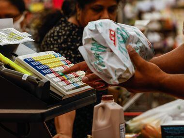 An H-E-B A cashier records a customer's purchase at the new store that opened its doors to...