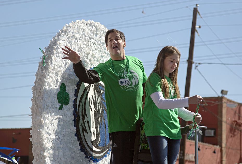 Dallas Mavericks owner Mark Cuban (left) threw beads from the grand marshal float during the...