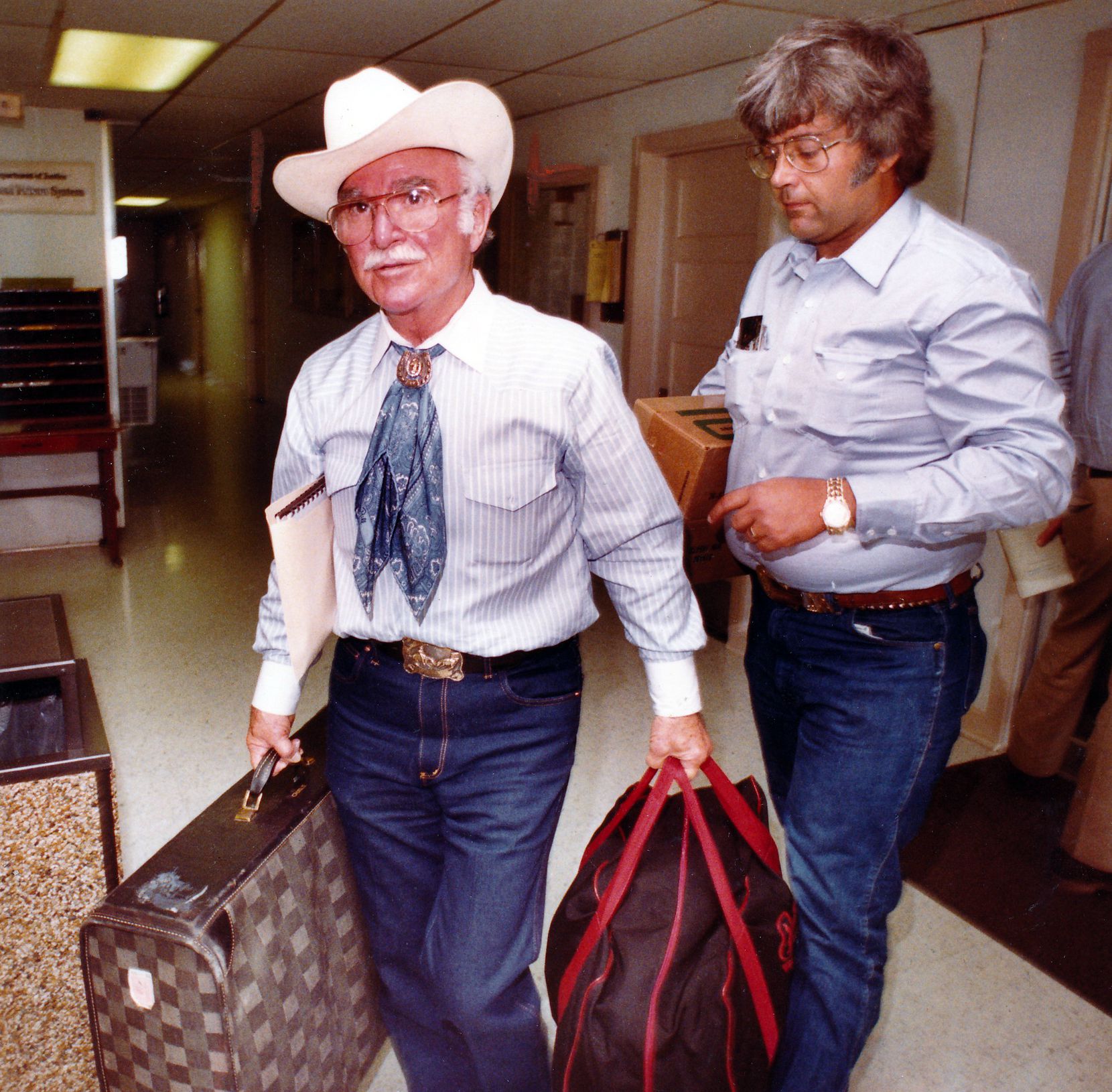 Rex Cauble (left) and his son Lewis carry Cauble's belongings down a hallway in the federal...
