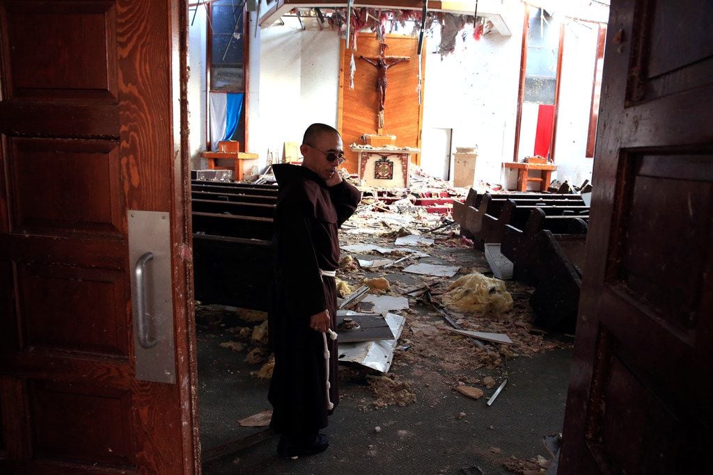 Fr. John Tran Nguyen looks around the heavily damaged St. Peter Catholic Church in Rockport...