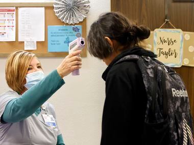 RN Stephanie Taylor checks a student’s temperature at Terrell Sr. High’s east campus office...