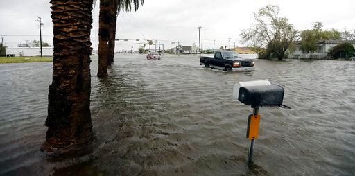 Dos vehículos cruzan una zona inundada tras el paso del huracán Harvey el sábado 26 de...