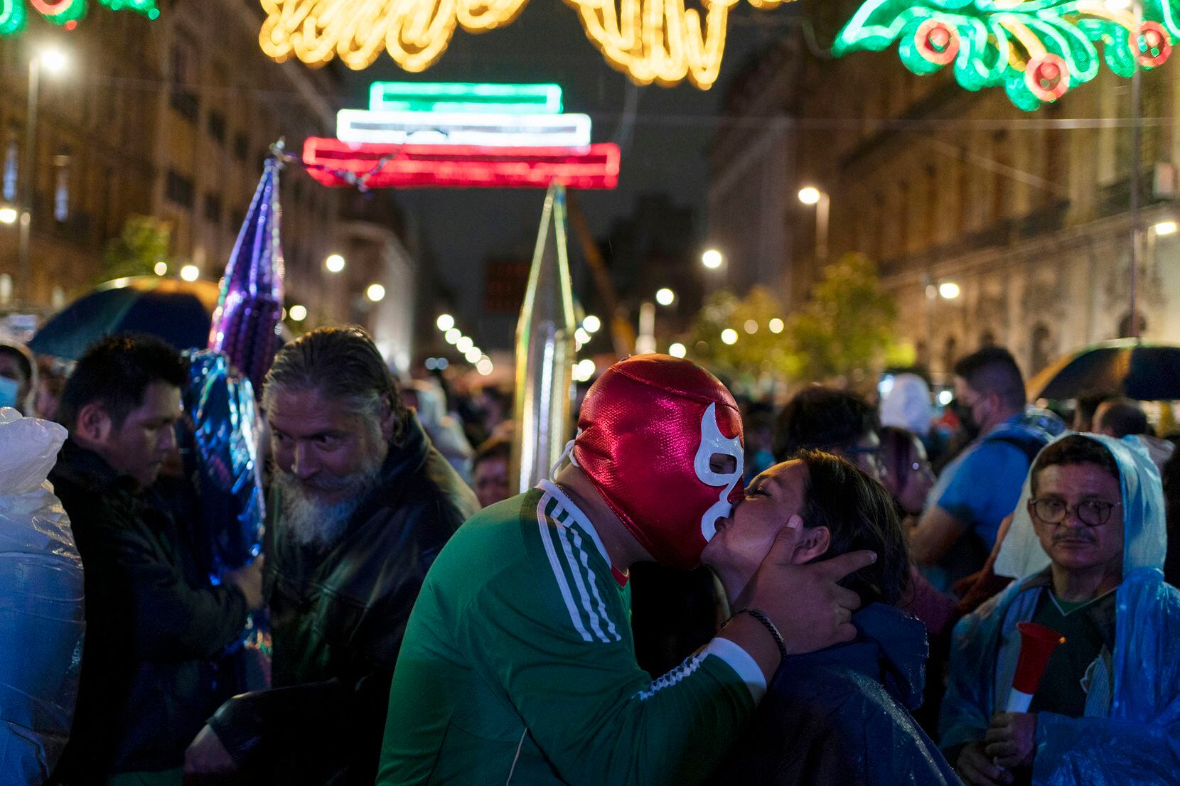 Un hombre con una máscara de luchador besa a una mujer en las celebraciones del Día de la...