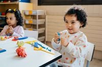 Cute multiracial toddlers sit at a table and play with modeling clay in a kindergarten...